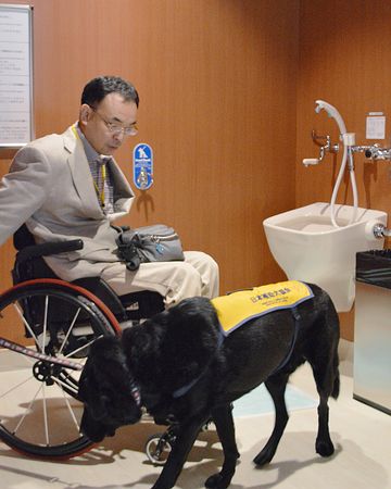 나리타 공항에 설치된 보조견 전용 화장실, 시연 중인 휠체어 장애인과 보조견.